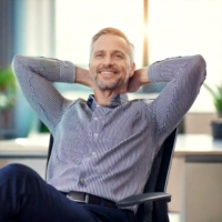 Firefly Ein Mann, ungefähr 45 Jahre, entspannt sich im Büro auf seinem Stuhl, die Arme hinter den Ko